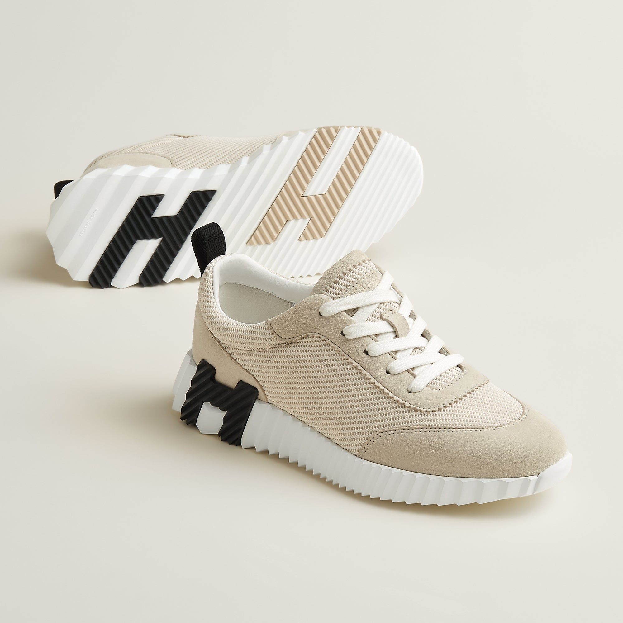 Beige sneakers with black and white accents on a light beige background